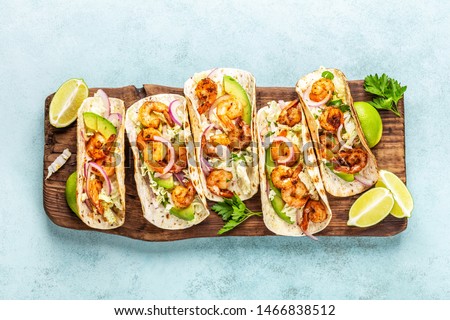 Shrimp tacos. Seafood fajitas with cabbage, onion, parsley in tortillas served on wooden cutting board