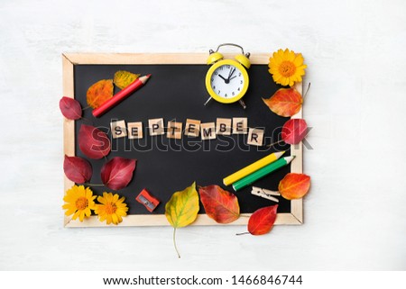 September time concept. notebook, pencil, clock alarm, flowers, autumn leaves, black chalkboard. Symbol of education, starting school, back to school. 1 september. beginning of school year. flat lay