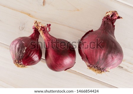 Group of three whole stale red onion flatlay on white wood