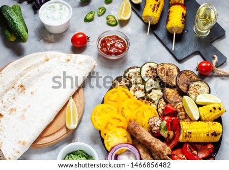 Assorted delicious grilled vegetables and meat on a concrete background. Summer food.