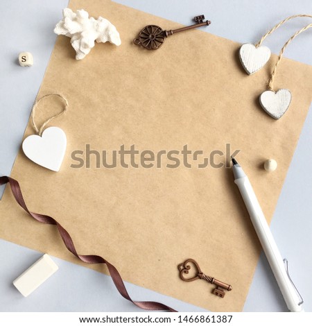 Background "Flat Layout Style" with grey desk, craft paper, white pencil, white wooden hearts, brown ribbon, eraser, coral and vintage keys