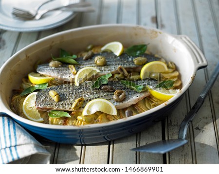 Striped Bass With Potatoes and Olives in a Casserole Dish 