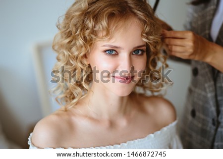 Backstage photo, preparation of a blonde young model woman with hair stylist