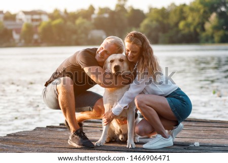 Couple with dog on a pear looking for sunset