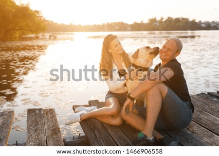Couple with dog on a pear looking for sunset