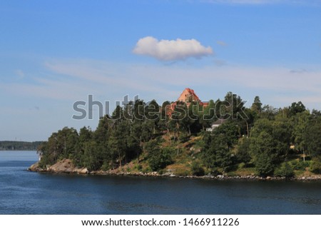 White cloud over the red roof of the house. Island in Scandinavian fjords with a residential house.