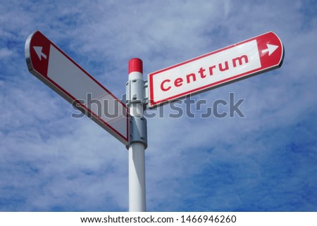 red direction sign on the pole against the blue cloudy sky. white arrow signal against heaven with clods. Centrum. empty frame