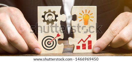 Businessman collects puzzles with the image of the attributes of doing business. Strategy planning concept. Organization of the process. Creating a business model. Management. Research, marketing. Royalty-Free Stock Photo #1466969450