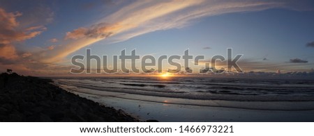Sunset at Hokitika beach with clouds and golden sky on the South Island of New Zealand.