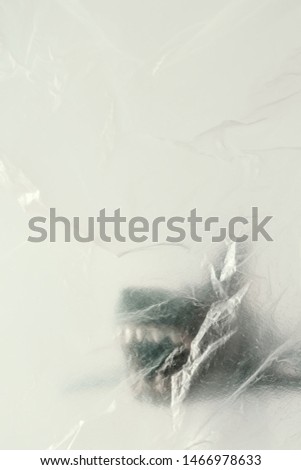 Shark( toy model) behind the transparent and crumpled plastic ,with copy space.Creative concept background for environmentalism and 
 plastic awareness.