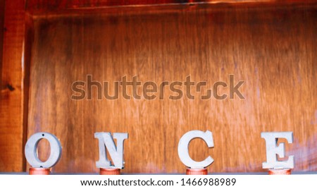 4 letters on bottle caps spelling the word "Once" in front of a wooden background