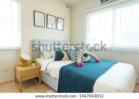 Interior of boy teen's bedroom with robot doll on bed and blue blanket.