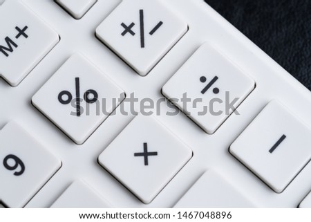 Closed up of white calculator buttons such as percentage, plus, minus, multiply and divind on black leather using as maths, investment banking and accounting.