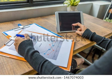 Hands using tablet and pointing at diagram business document
