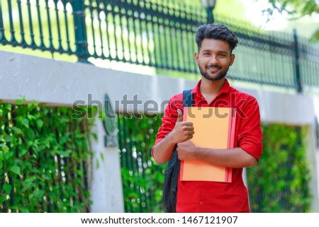 young indian collage student standing at collage campus and showing thumbs up.