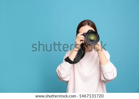 Professional photographer taking picture on light blue background. Space for text