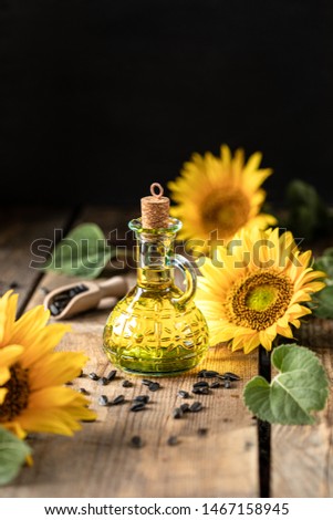 Sunflower oil in a bottle glass with seeds and flowers of sunflower. on blurred background
