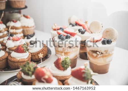 candy buffet with white souffle in glasses. Toned image.Buffet with sweets. Cakes with strawberries and blueberry. Sweet table for banquets, weddings, parties. Candy bar.The holiday table decoration.