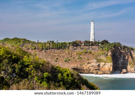 Beautiful beach with cliff, lighthouse tower and blue sky background view in high resolution. Taken in July 2019,  Gunung kidul province, Java island, Indonesia