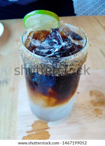 Americano iced coffee, Americano is cold in a clear glass with lime and sugar granules.