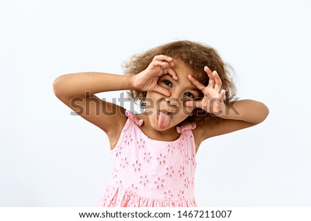 Making face,funny  foolishes portrait of little African American girl, against white background.  Royalty-Free Stock Photo #1467211007