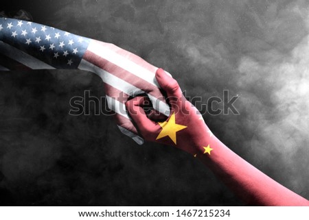 Handshake of hands of two men with Chinese skin and America skin over black wall background. Trade war Chinese against America