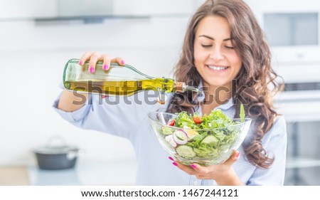 Young woman pouring olive oil in to the salad. Healthy lifestyle eating concept. Royalty-Free Stock Photo #1467244121