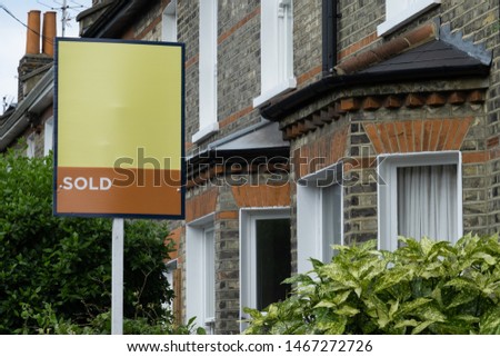 Estate agent 'SOLD' sign outside row of urban terraced houses