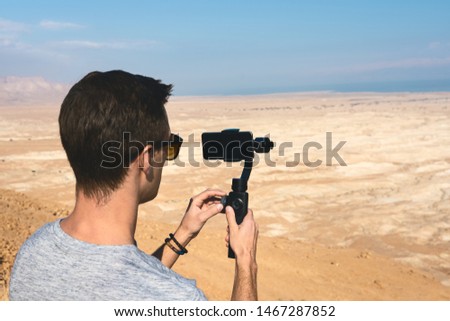 filming the desert lanscape with a phone and a gimbal. Dead sea in the background Royalty-Free Stock Photo #1467287852
