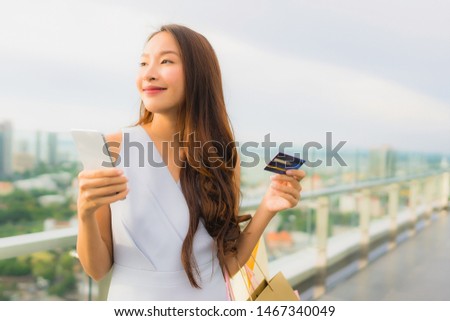 Portrait beautiful young asian woman happy and smile with credit card and mobile or smart phone and shopping bag from department store shop and mall