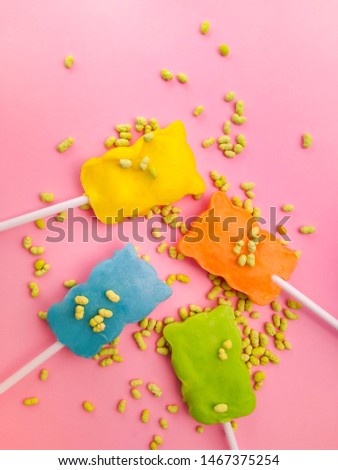 Close-up image of four colorful teddy bear shape lollipop candy on pink colored background with copy space.