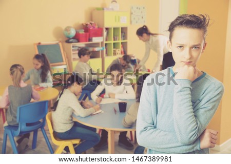 Portrait of upset schoolboy, boys and girls in classroom 