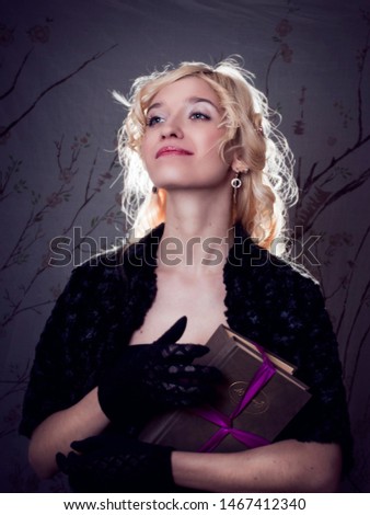 A young blonde with long hair smiles, holds books in her hands. Black and white portrait