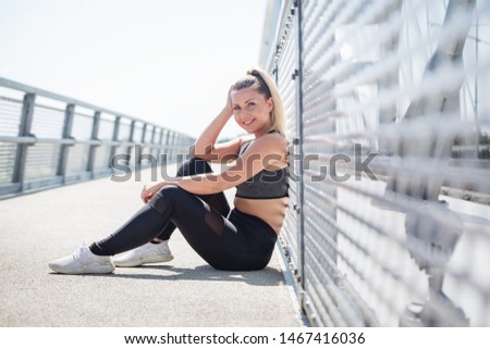 
Pretty young girl sitting on the bridge and getting ready for her workout on a nice sunny day