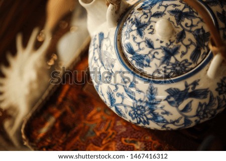 Porcelain blue and white teapot close up on interesting tray with shells in background