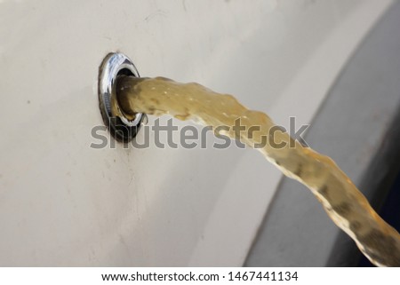 Ship bilge pump pumps out water from the boat through the drain scupper in the Board close-up Royalty-Free Stock Photo #1467441134