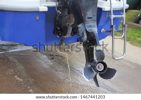 Lifting the motor boat on the trailer from the water - feed with outboard motor and open drain scupper on the background of wet concrete slip Royalty-Free Stock Photo #1467441203