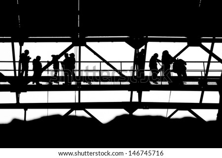 Silhouettes of people against an iron design of the industrial building