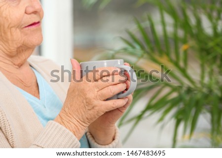 Closeup view of elderly woman with cup of tea in nursing home, space for text. Assisting senior generation