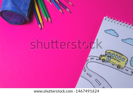 Notebook with a picture of a school bus on a crimson background. color pencil