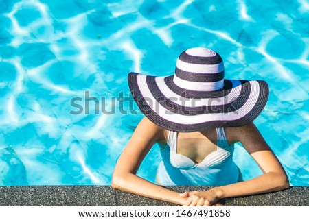 Beautiful young asian woman with hat in swimming pool for travel and vacation concept