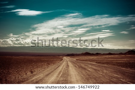 Empty rural road going through prairie under cloudy sky in Charyn canyon. State National Paleontology Park in Kazakhstan. Vintage style processing image Royalty-Free Stock Photo #146749922