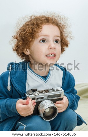 Small child using photo camera, girl crumbling with old camera, two year old child with electronic device