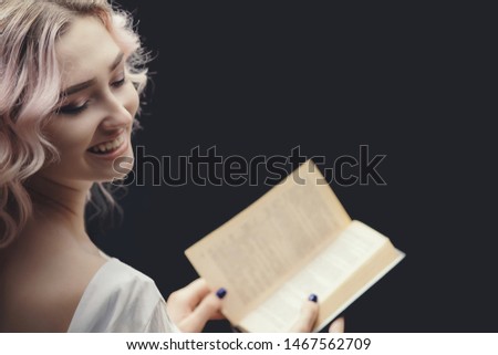 blonde happy girl holding open book, young beautiful woman reading a novel, concept of hobby, relaxation on black background