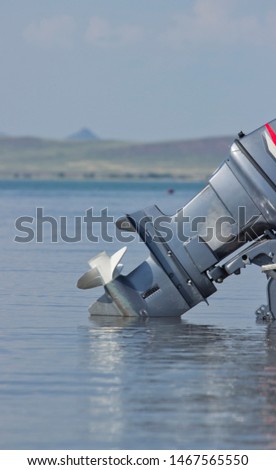 Outboard motor lowered into the water. A boat engine is waiting to be started.  Royalty-Free Stock Photo #1467565550
