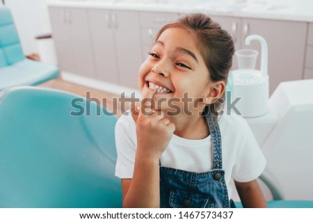 Mixed race little patient showing her perfect toothy smile while sitting dentists chair Royalty-Free Stock Photo #1467573437
