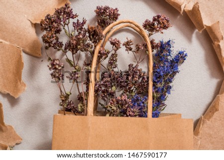 Kraft package, reusable environmental packaging, homemade tea flowers. mint lemon balm and hyssop. Torn paper as background. hole in kraft paper. Flat Lay Copy space