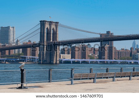 Sunny day view of Brooklyn Bridge, American flag, East River and Manhattan Skyline with blue sky
