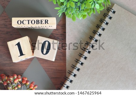 October 10. Date of October month. Number Cube with a flower and notebook on Diamond wood table for the background.