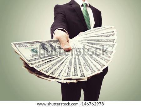 Business Man Displaying a Spread of Cash over a green vintage background Royalty-Free Stock Photo #146762978
